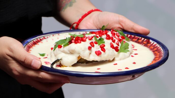 Preparación de chile en nogada tradicional poblano con nogada y granada en festival gastronómico de Cholula