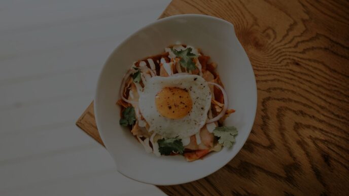Plato de chilaquiles verdes con crema y queso fresco en restaurante de la Ciudad de México